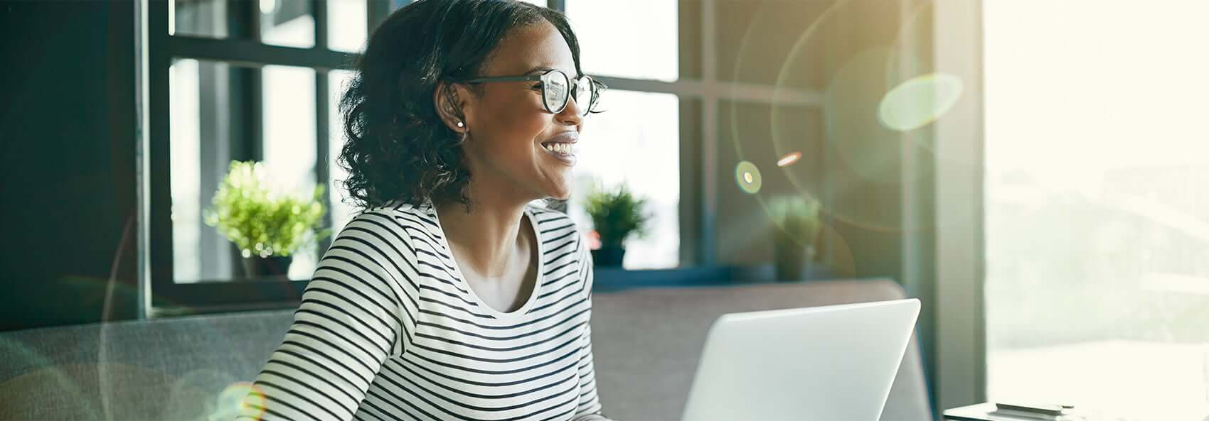 woman with glasses smiling while working on computer