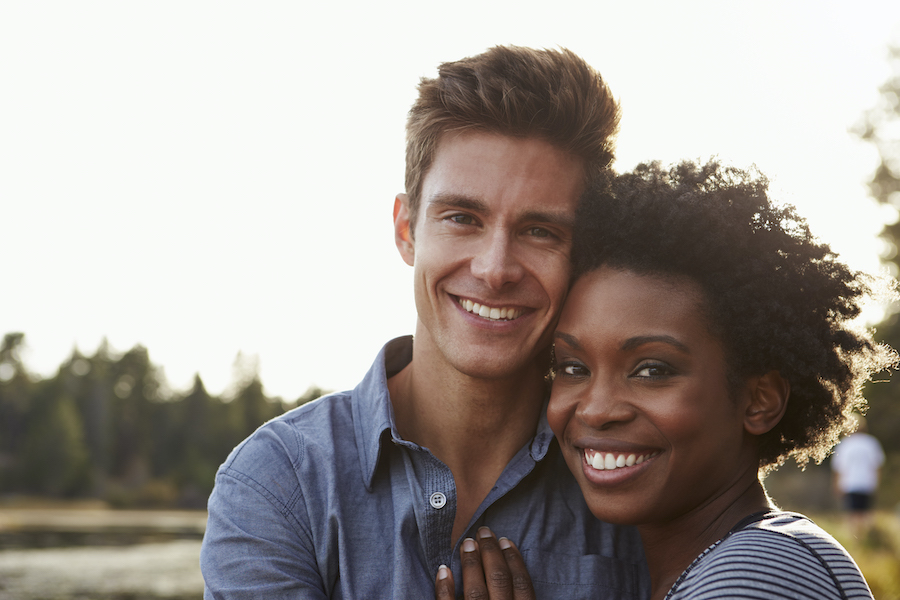 Black and white couple smile as they embrace outside at dentist in hermitage