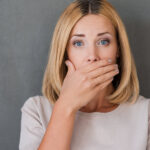 Photo of a woman covering her mouth with her hand.